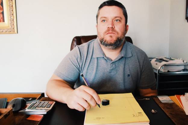 Man at a Desk with a Calculator and Yellow Notebook