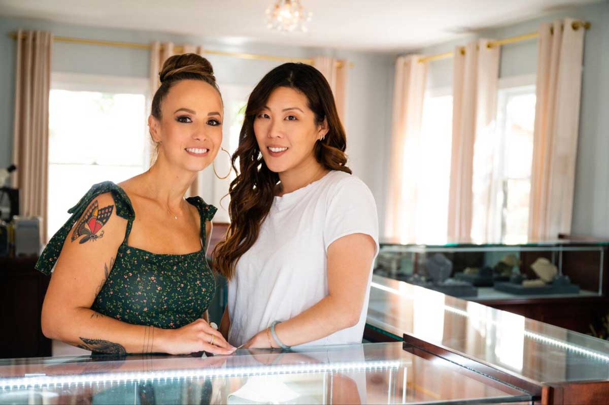 A photo of two women standing in front of a jewelry case. The women are Jenny and Amy the owners of Diamonds Forever a jewelry store in San Diego