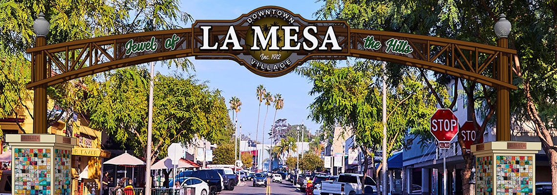 A street view of the La Mesa Village, including a sign introducing the shopping village